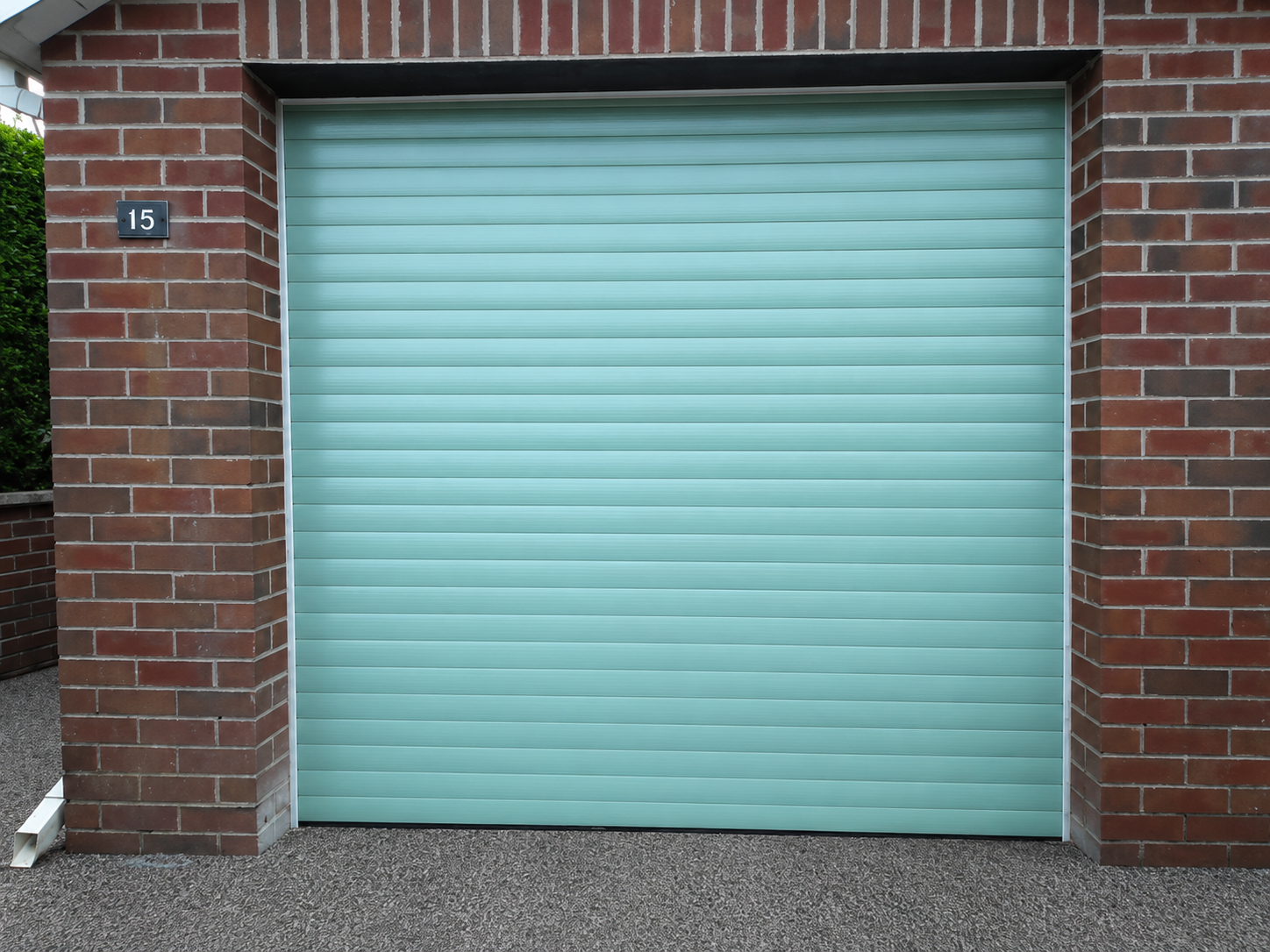Chartwell green electric roller garage door on a red brick single garage in Faringdon